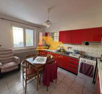 A kitchen with a red cabinet in a family house, equipped with a table and a chair.