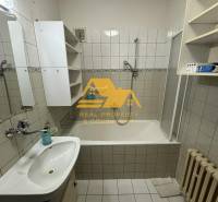 Bathroom with a bathtub, sink, white cabinets, and a radiator in a family house.