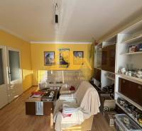 Living room in a family house with a white sofa, wooden decor flooring, yellow walls.