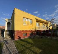 Yellow family house in Nové Zámky on a street with a landscaped garden and walkway.