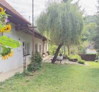 A family house in Krivosúd-Bodovka with a landscaped garden and a bench under a tree.