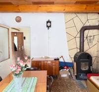 Interior of a family house with a tiled stove, wooden ceiling, and a dining table with flowers.