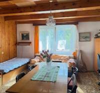 A room in a family house with wooden beams, a dining table, and two beds.