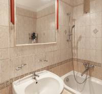 A bathroom with a bathtub, a sink, and a mirror in a three-room apartment.