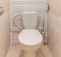A toilet with beige tiles in a 3-room apartment, in a clean and simple design.