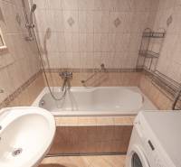 A bathroom in a 3-room apartment with tiles, a bathtub, and a washing machine.