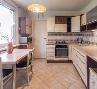 A kitchen with mosaic tiles and a table in a 3-room apartment is equipped with appliances.