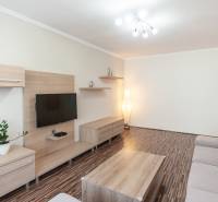 Living room of a three-room apartment with a wooden decor floor and a gray sofa.