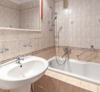 A bathroom in a 3-room apartment with a bathtub, tiles, and a sink, complemented by a mirror.