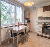 A kitchen in a 3-room apartment with a tiled wall and a floor with a wooden decor.