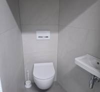 Bathroom in a family house with a toilet, sink, and white tiles.