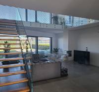 Living room in a family house with a staircase and glass railings.