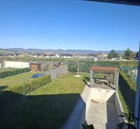 The garden of a family house in Zvončín with a gazebo and a swimming pool, overlooking the hills.