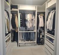 A wardrobe with clothes and dressers in a family house with a wooden decor floor.