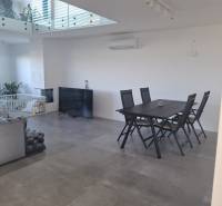 Interior of a family house with gray tiles, a dining table, and a television.