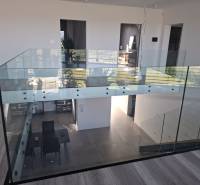 Interior of a family house with glass railings and flooring with a wooden decor.