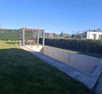 The garden of a family house in Zvončín with a pergola and an unfinished swimming pool.