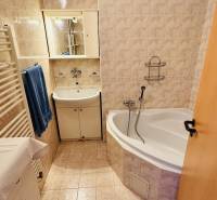 Bathroom of a 3-room apartment with a bathtub, sink, and beige tiles.
