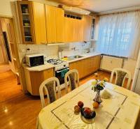 A kitchen in a 3-room apartment with a wooden decor floor and a dining table.