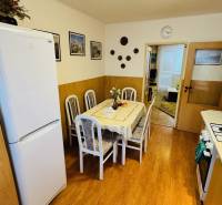 A kitchen in a 3-room apartment with a dining table and a wooden decor floor.