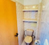 A toilet with ceramic tiles and storage shelves, part of a 3-room apartment.