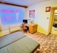 A room in a 3-room apartment with a carpet, a desk, and a bed.