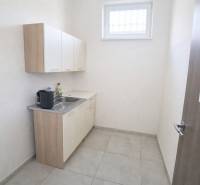 A kitchenette with a sink and cabinets in commercial premises, light tiles.