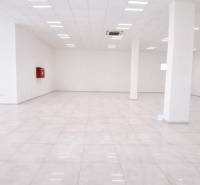 Spacious commercial spaces with white flooring and columns, bright lighting.