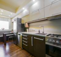 A kitchen in a 3-room apartment with a wooden decor floor and corner seating.