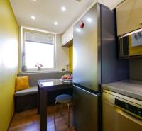 A kitchen in a 3-room apartment with a wooden decor floor, a dining area with a bench.