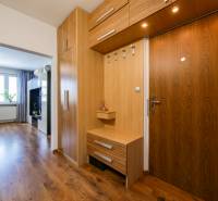 Interior of a 3-room apartment with a hallway, wooden cabinets, and flooring with a wood decor.
