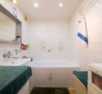 Bathroom in a 3-room apartment with a bathtub, sink, white tiles, and a green carpet.