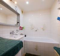 Bathroom in a 3-room apartment with a bathtub, sink, and white tiles.