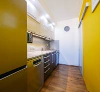 A kitchen in a 3-room apartment with a colored wall and a floor with a wood decor.