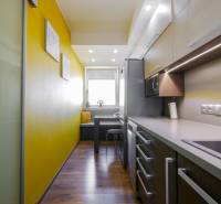 A kitchen in a 3-room apartment with a wooden decor floor and yellow walls.