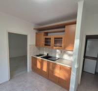 A kitchen unit with ceramic tiles in a studio apartment with a wooden decor floor.