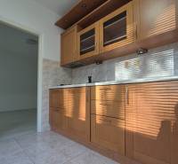 A kitchen unit in a studio apartment with tiles and cabinets with a wood decor.