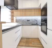 A kitchen in a 3-room apartment with white cabinets and a wood-patterned floor.