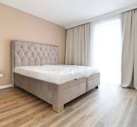 A bedroom with a bed and a wooden decor floor in a three-room apartment.
