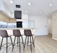 A kitchen with a bar counter and a wooden decor floor in a 3-room apartment.