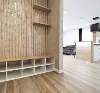 Interior of a 3-room apartment with wood-patterned flooring, kitchen, and living area.