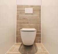 A toilet with wooden decor and white tiles in a 3-room apartment.