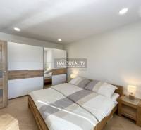 A bedroom with wood-patterned flooring in a studio apartment, light bed and wardrobe.