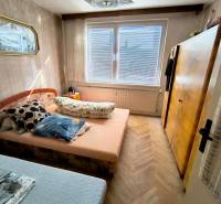 A bedroom in a 3-room apartment with a bed, a cabinet, and a floor with a wooden decor.