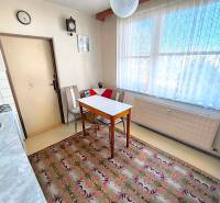 A kitchen in a 3-room apartment with a dining table, chairs, and a carpet.