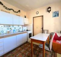 A kitchen in a 3-room apartment with white cabinets and decorative tiles.
