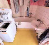 Bathroom with a sink, bathtub, and washing machine in a 3-room apartment.
