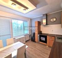 A kitchen in a 3-room apartment with a wooden decor floor and a dining table.