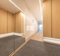A hallway in a 3-room apartment with a wooden decor floor and a mirror.
