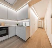 A kitchen in a 3-room apartment with a wooden decor floor and light furniture.